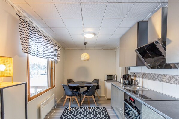 A compact kitchen with a dining area, a microwave, and a built-in oven.