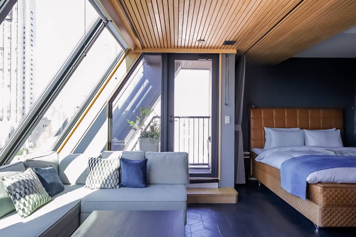 Una habitación de hotel moderna con balcón, cama, sofá y vistas a la ciudad.