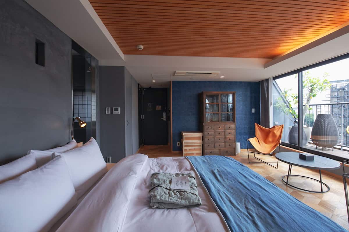 Un dormitorio moderno con una cama grande, un aparador, una silla y vistas de la ciudad.
