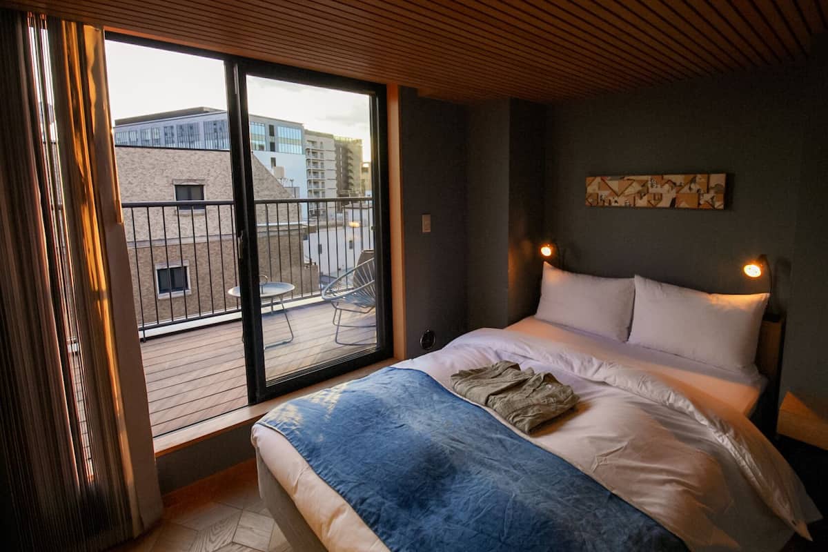 Un dormitorio con un ventanal grande, una cama y vistas de la ciudad.