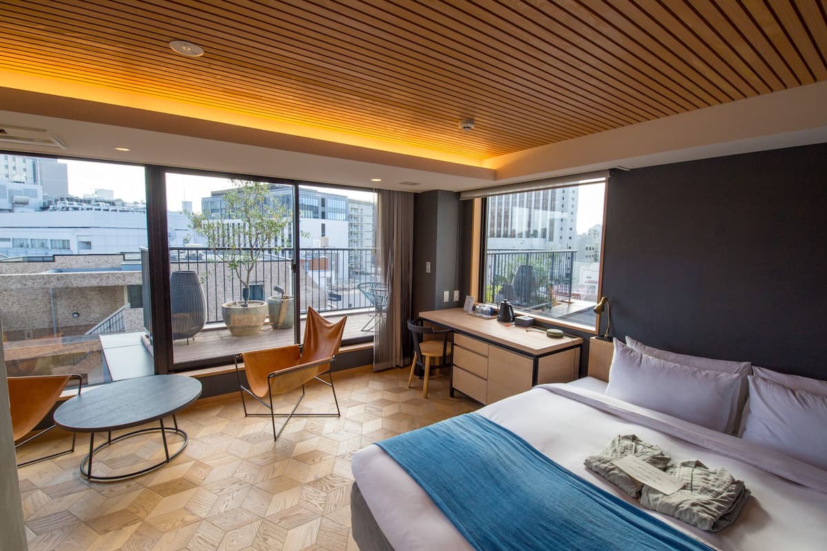 Habitación de hotel moderna con una cama grande, un escritorio y un balcón con vistas a la ciudad.