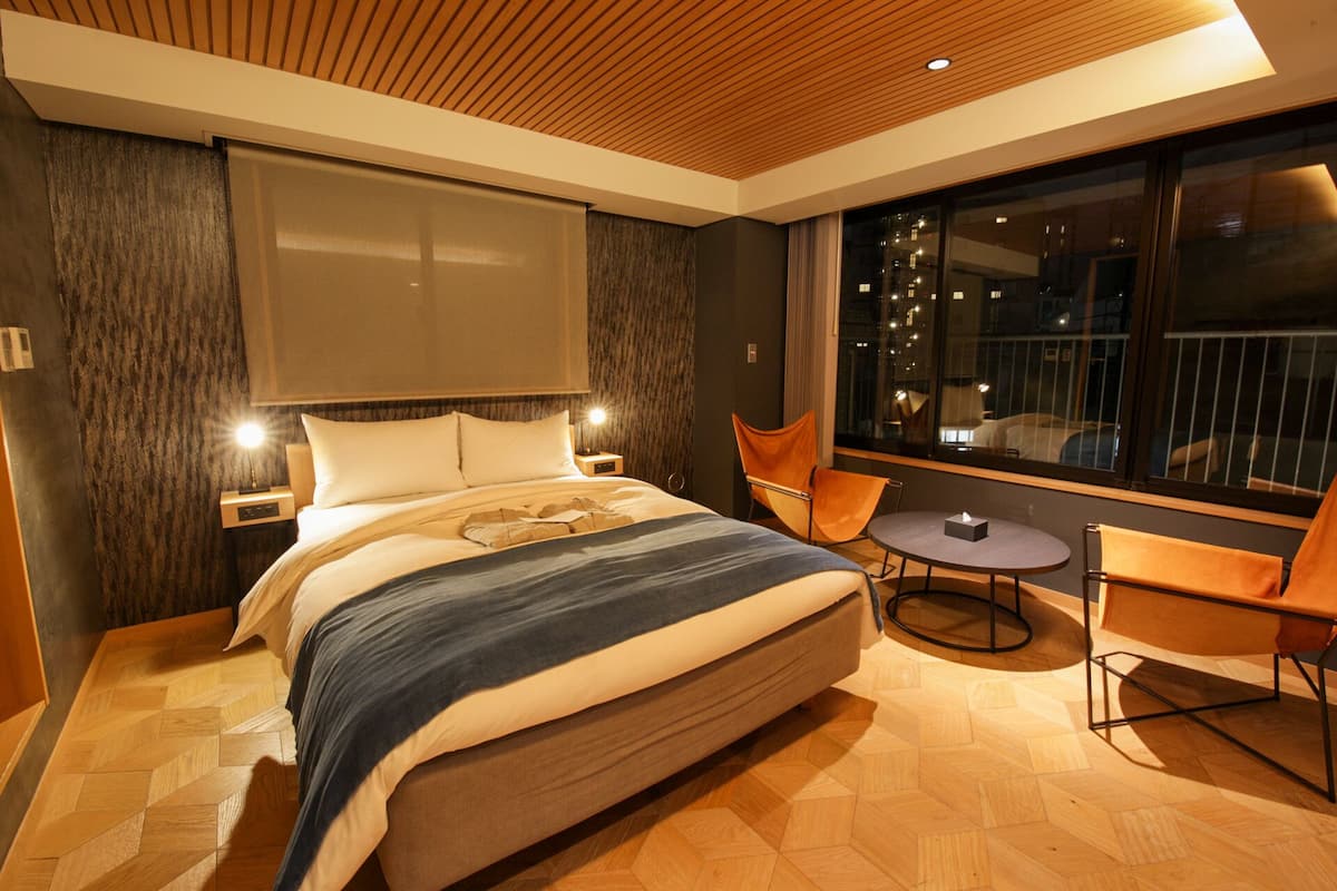 Una habitación de hotel moderna con una cama grande, una mesita redonda pequeña y dos sillas.