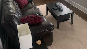 A living room with a leather sofa, a flat-screen TV, and a coffee table.