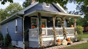 A house with a porch decorated with pumpkins and corn stalks.