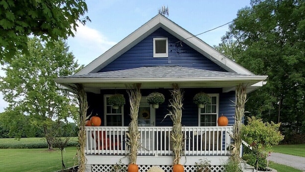 A two-story house with a porch, surrounded by a well-maintained lawn and trees.