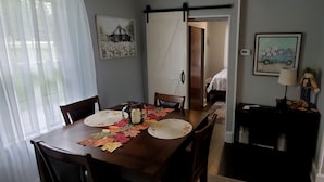 A dining room with a wooden table set for four, chairs, and a decorative centerpiece.