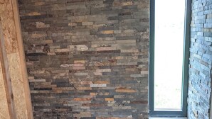 A room with a stone wall, a window, and a fireplace.