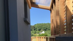 A wooden deck with a view of a house and forest.