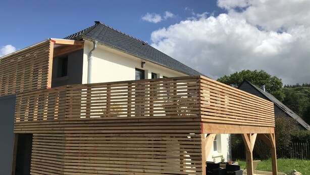 A two-story house with a wooden deck and a covered patio area.
