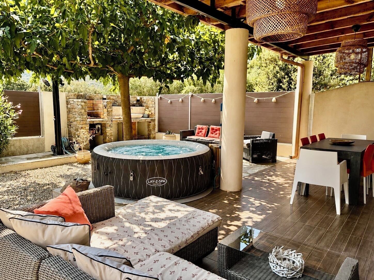 An outdoor patio area with a hot tub, wicker furniture, and a stone wall.
