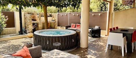 An outdoor patio area with a hot tub, wicker furniture, and a stone wall.