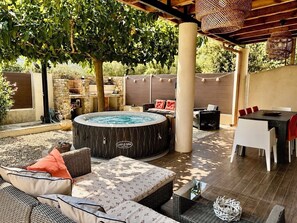 An outdoor patio area with a hot tub, wicker furniture, and a stone wall. - ☀ VILLA CARLETTI: 7 PEOPLE - 3 BEDROOMS - 5-MINUTE DRIVE TO THE BEACHES AND SAINT FLORENT (Oletta)
