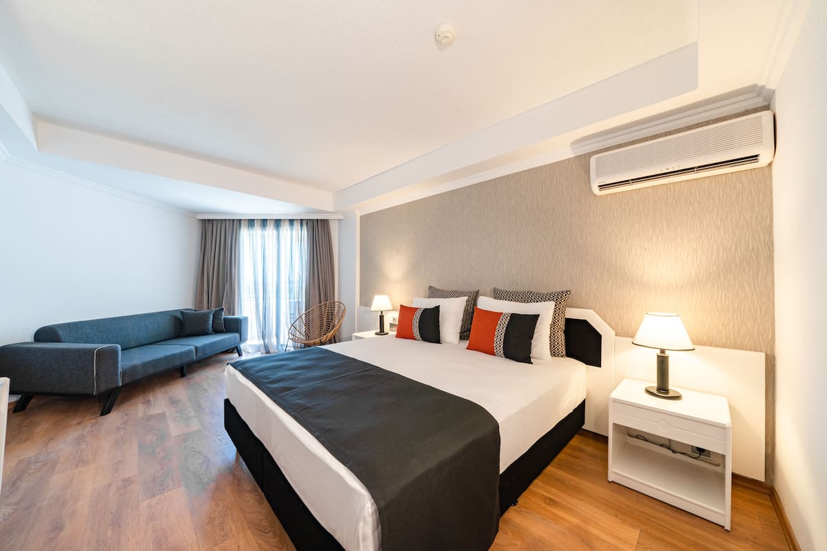 Une chambre d’hôtel moderne équipée d’un grand lit, d’un canapé, d’une table de chevet et d’un appareil de climatisation.