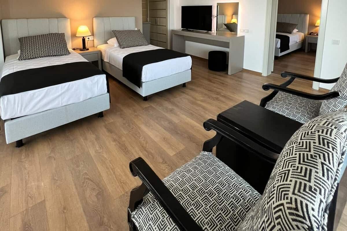Une chambre d’hôtel moderne équipée de deux lits, d’une télévision, d’un canapé et d’un bureau.