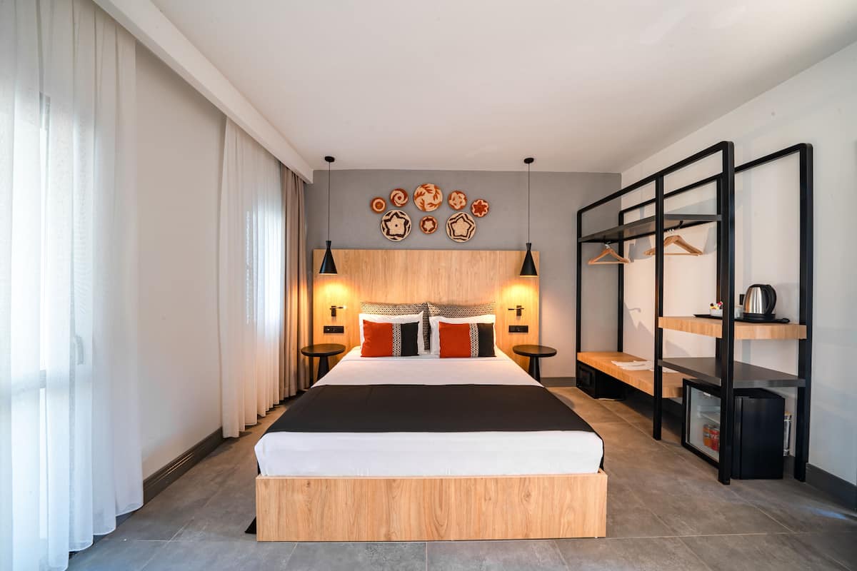 Une chambre d’hôtel moderne, dotée d’un grand lit, de tables de chevet, d’un bureau et d’une armoire.
