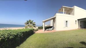 Ein zweistöckiges Haus mit einem Balkon mit Blick auf einen Strand.