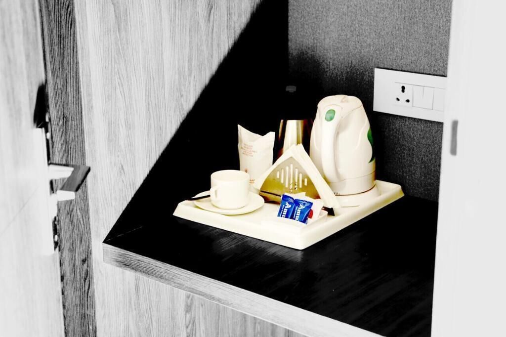 A breakfast tray with a cup, a small bag, and a bottle on a black countertop.