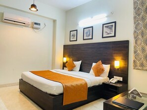 A hotel room with a large bed, bedside lamps, a telephone, and a small table. - Hotel Kanishk (Bawal)