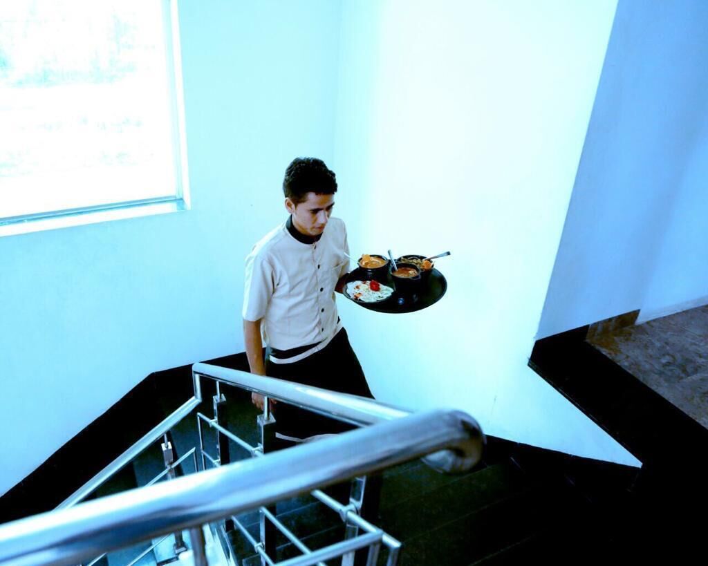 Una persona baja una escalera llevando una bandeja con comida.