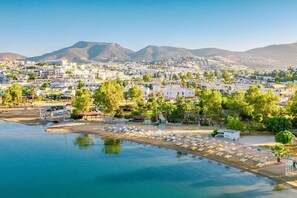 A coastal resort with a marina, beach, and mountain backdrop.
