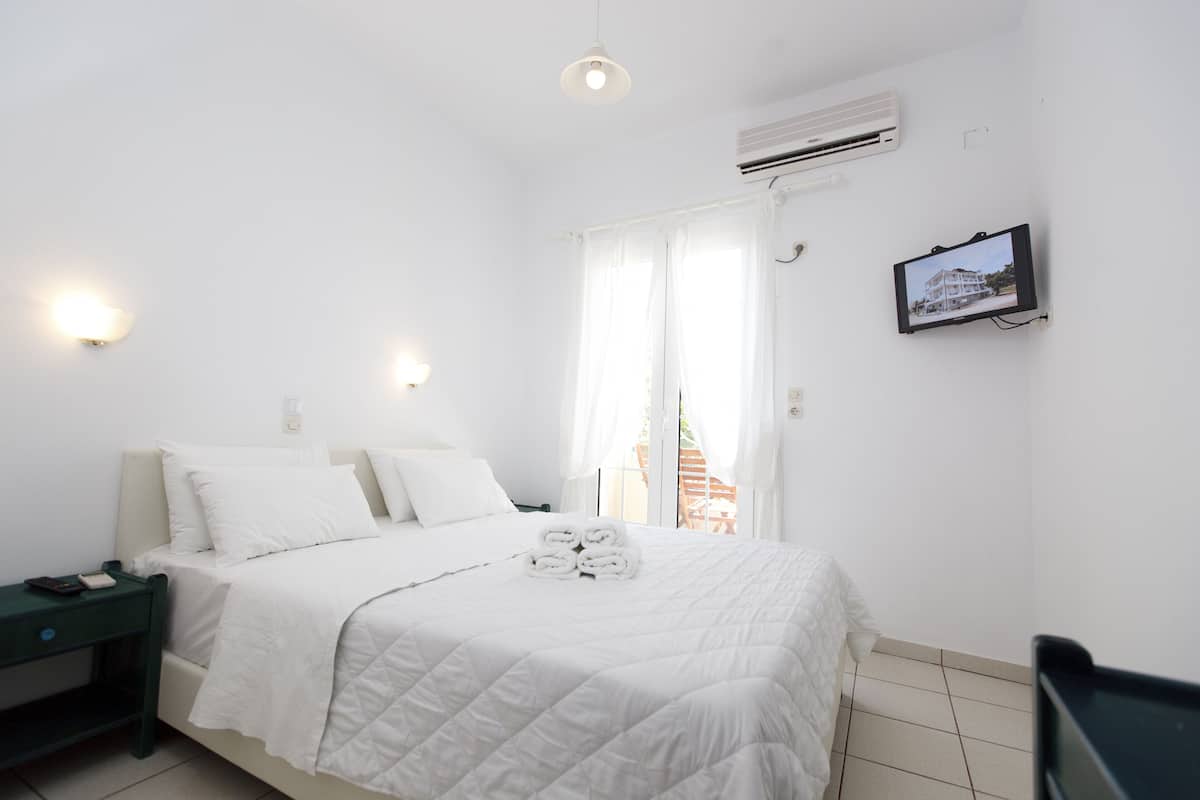 A hotel room with a bed, a TV, and a window with curtains.