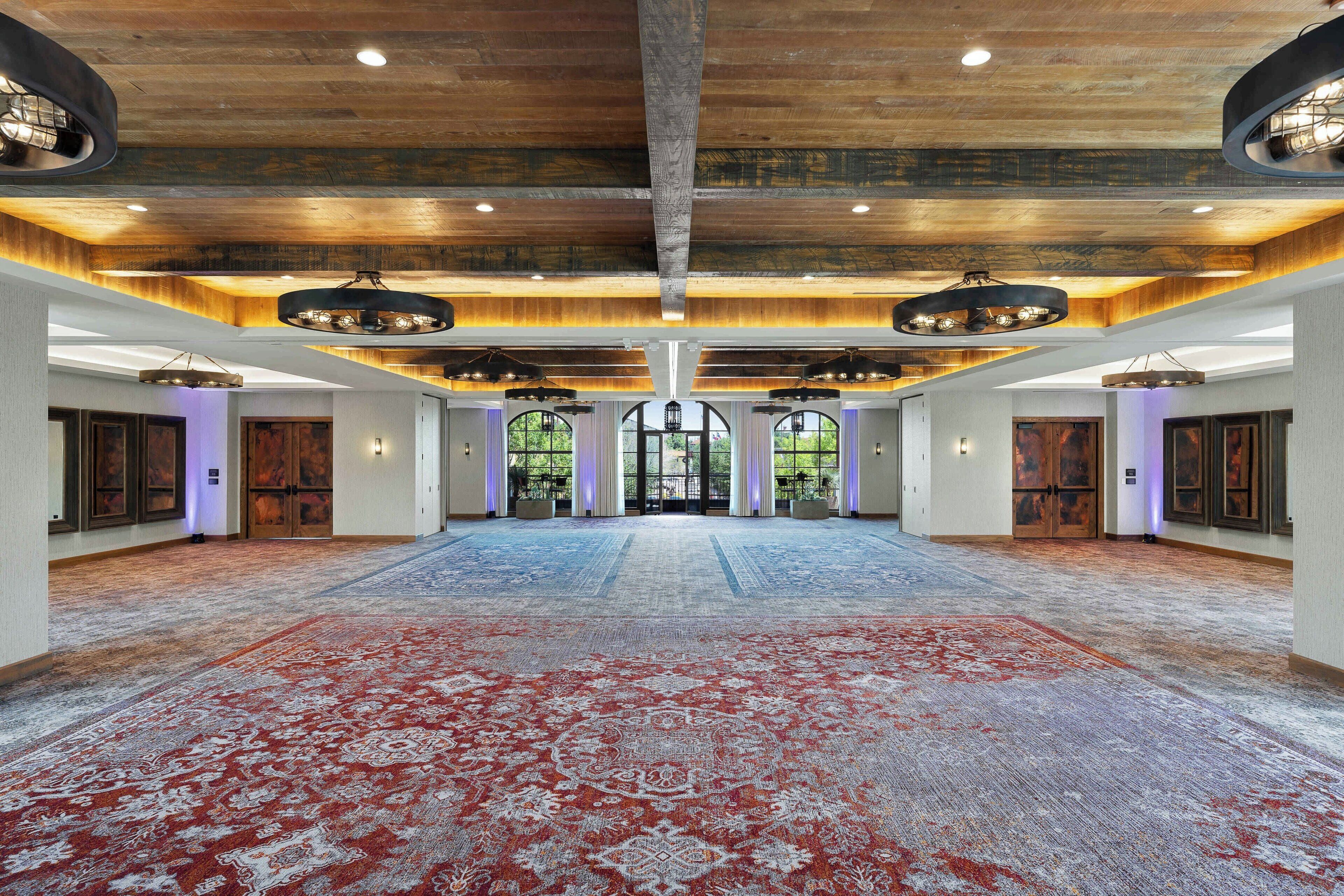A spacious hall with a large carpet, wooden ceiling, and multiple doors.
