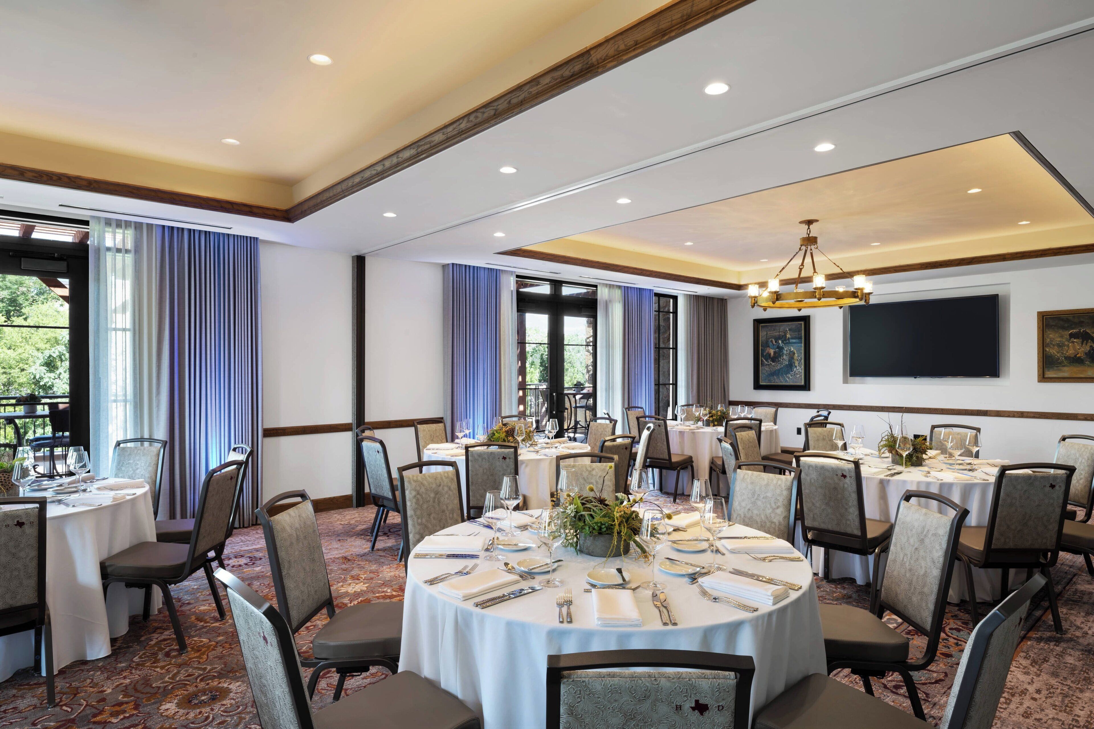 A conference room with round tables, chairs, and a chandelier.