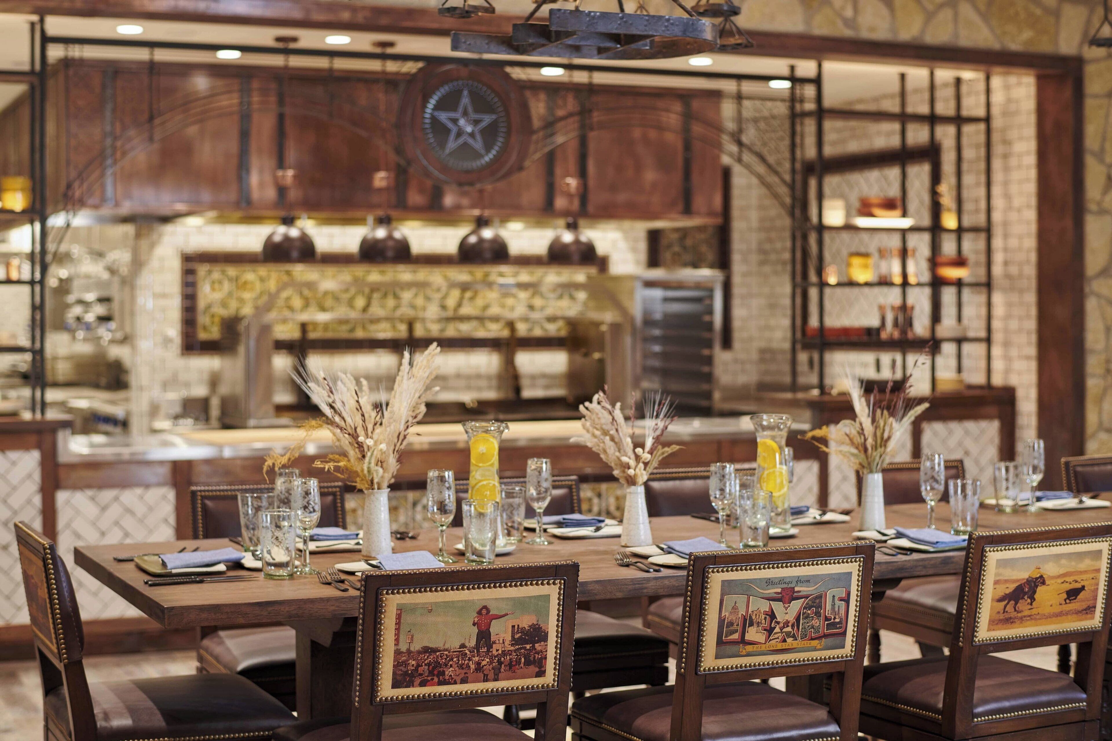 A dining area with a long table set for a meal, surrounded by chairs with framed pictures.