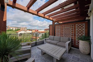 A balcony with a wooden pergola, a sofa, a table, and potted plants. - Hotel Drover, Autograph Collection (Fort Worth)
