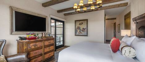 Un dormitorio con una cama grande, cómoda de madera y televisor de pantalla plana montado en la pared.