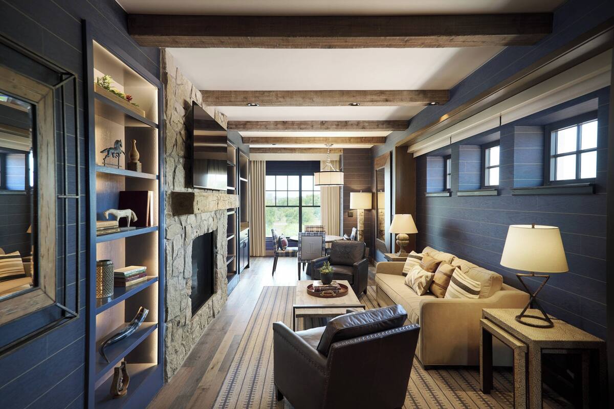A spacious living room with a stone fireplace, a sofa, a coffee table, and a bookshelf.