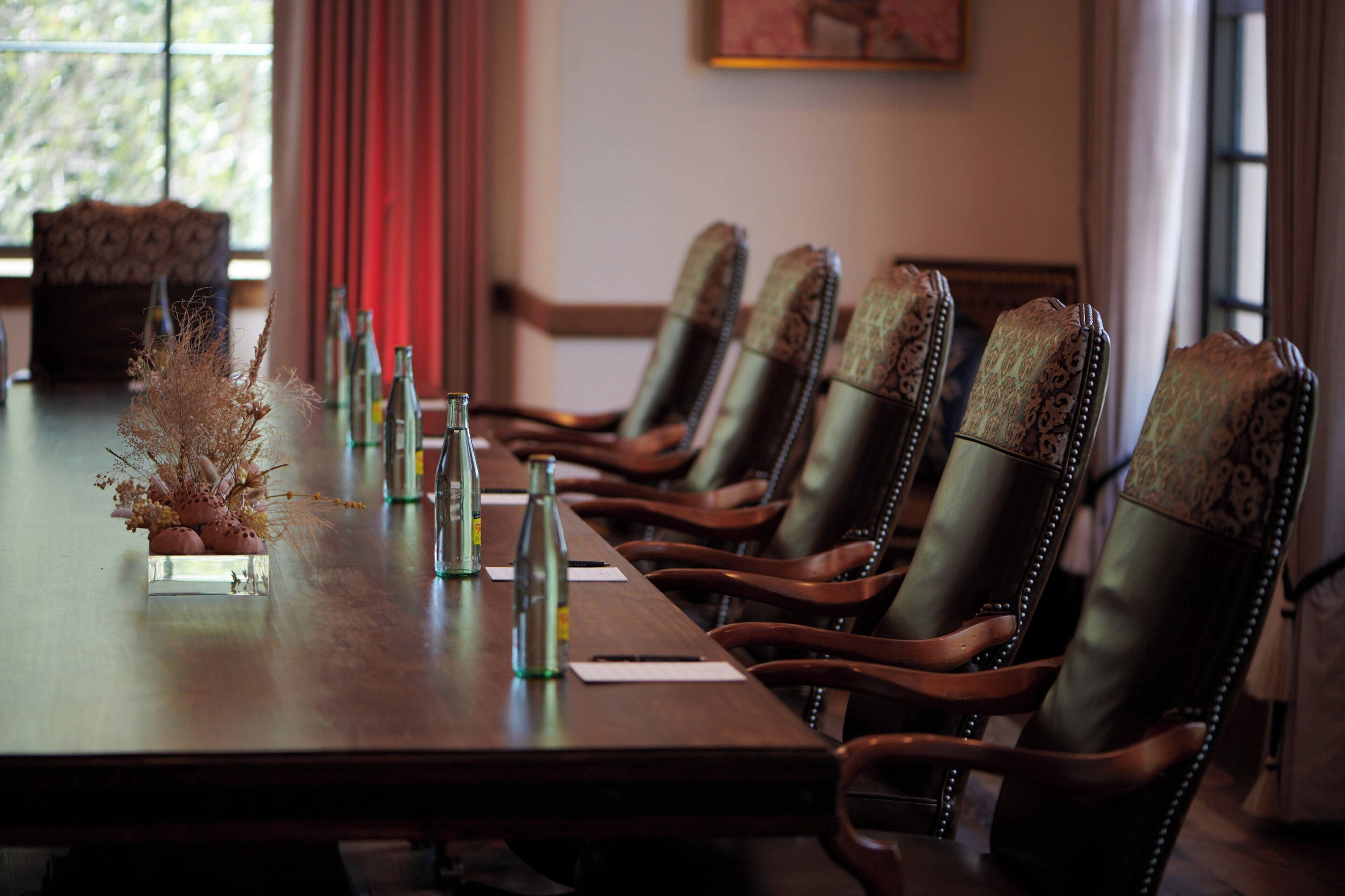 A conference table with chairs, bottles, and a decorative arrangement.