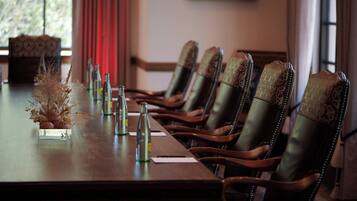 A conference table with chairs, bottles, and a decorative arrangement.