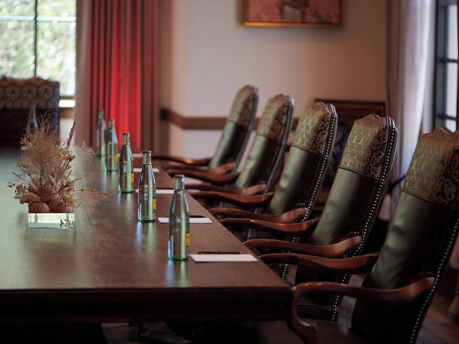 A conference table with chairs, bottles, and a decorative arrangement.