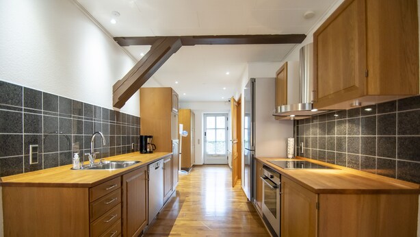 A modern kitchen with wooden cabinets, a tiled backsplash, and a wooden countertop. - City Center Luxury Getaway (Sønderborg)
