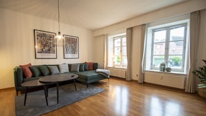 A modern living room with a green sofa, a round coffee table, and a large window with curtains. - City Center Luxury Getaway (Sønderborg)