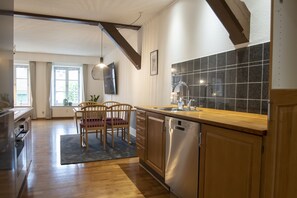 A modern kitchen with wooden cabinets, a stainless steel dishwasher, and a large window.
