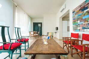 Un comedor con una mesa de madera, sillas con cojines rojos y una pared de ladrillo de colores.