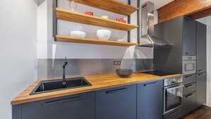 A modern kitchen with a wooden countertop, a stainless steel sink, and a built-in oven.