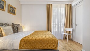 Une chambre à coucher comprenant un lit, une chaise, une armoire et deux tableaux encadrés accrochés au mur.