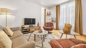 Un salon moderne comprenant un canapé, un fauteuil, une table basse, un téléviseur et des vases décoratifs.