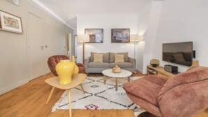 Un salon avec un canapé, deux lampes, un téléviseur et une table basse.