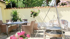 Eine Terrasse im Freien mit Korbmöbeln, einem runden Tisch und einem Schaukelstuhl.