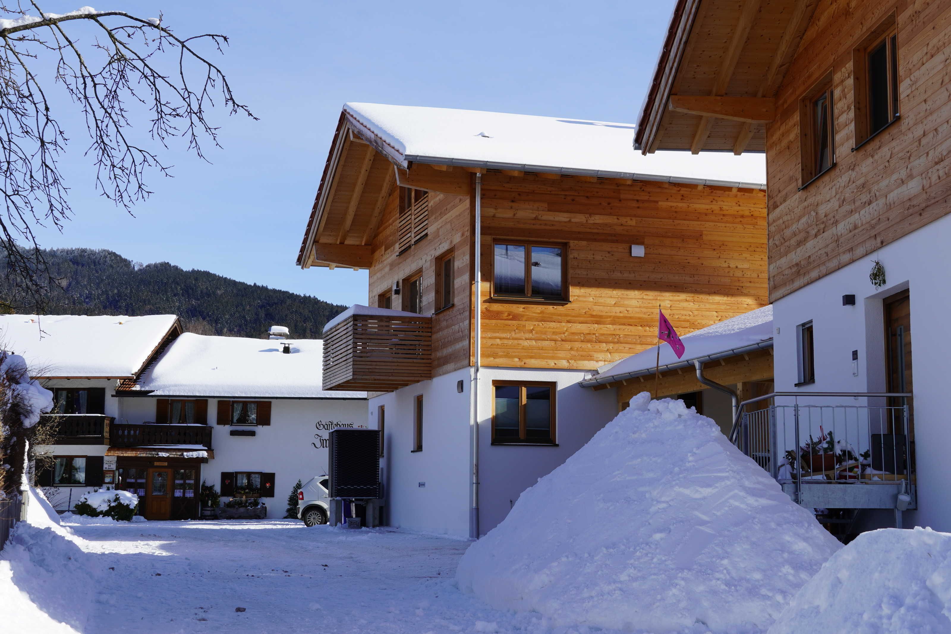 Un edificio di legno con tetto imbiancato dalla neve, un ingresso ben visibile e una bandiera.
