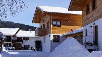 Un bâtiment en bois, avec un toit enneigé, une entrée bien visible et un drapeau.