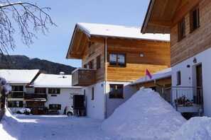 Ein hölzernes Gebäude mit schneebedecktem Dach, einem gut sichtbaren Eingang und einer Flagge.