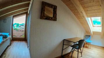 Une pièce de style loft avec un plafond en pente, une petite table avec des chaises, un lit et une grande fenêtre.
