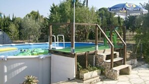 Une piscine avec un plongeoir, entourée d’une clôture en bois et bordée d’escaliers en pierre.