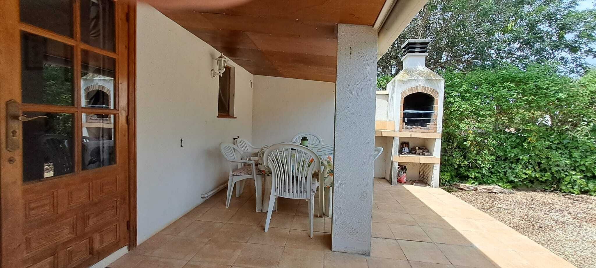 A covered patio with a table and chairs, a wooden door, and a brick oven.