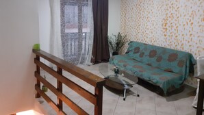 A living room with a sofa, a coffee table, a wooden railing, and a patterned wall. - Hospitality Home in Asimi , with great location (HERAKLEION,GRETE)